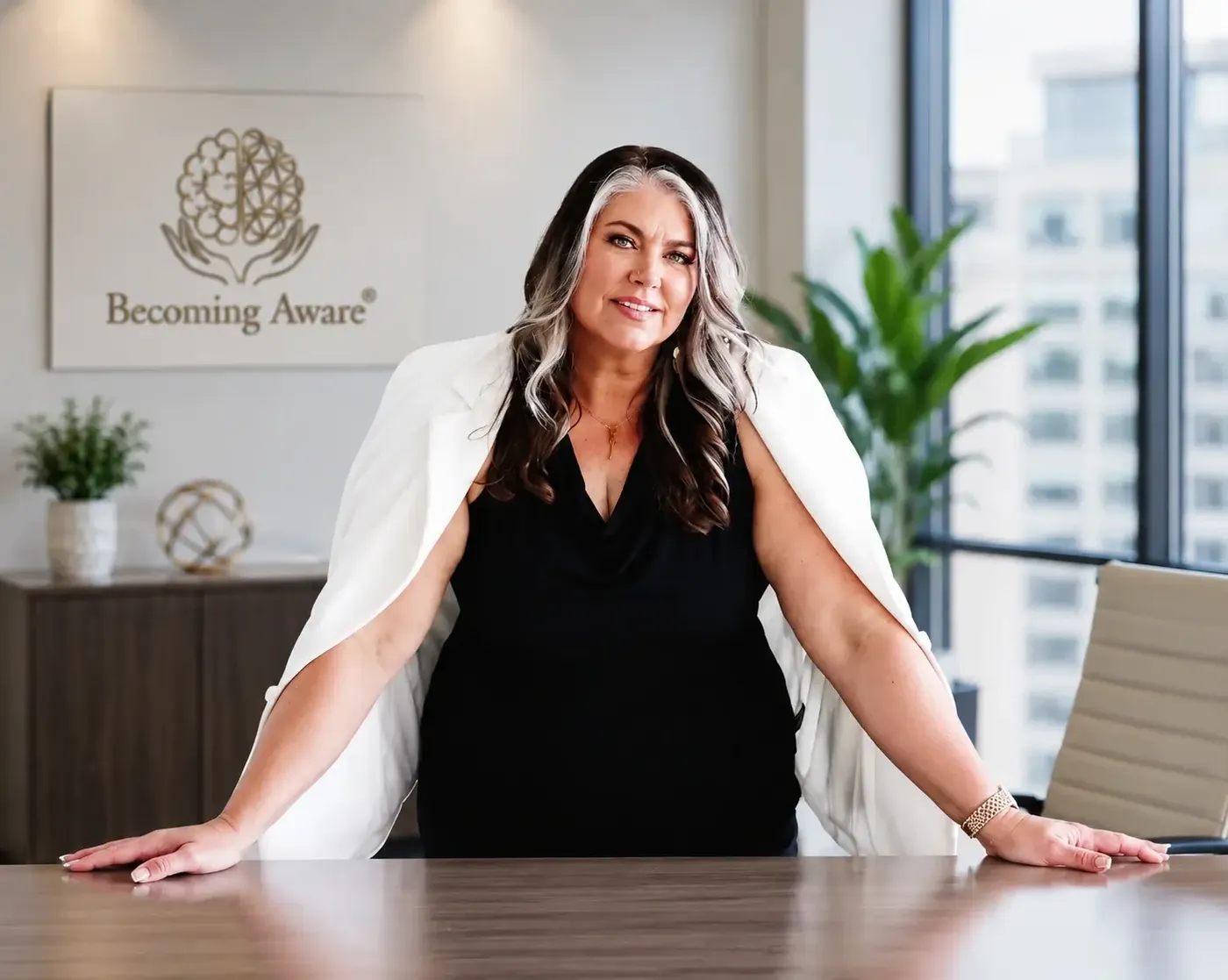Teresa Lodato leaning on a boardroom table in front of the Becoming Aware sign